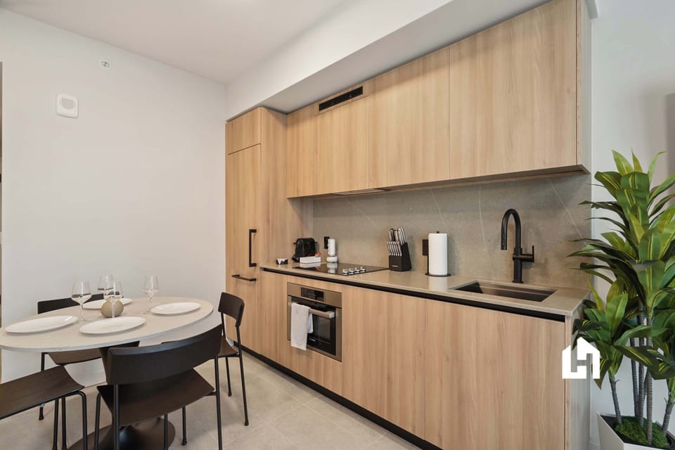Well-equipped kitchen with stove, sink, modern cabinetry and dining table
