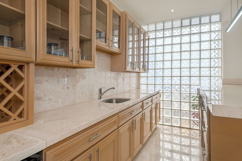 Gleaming marble counters and warm wood cabinetry invite you to prepare your favorite meals, while the stunning glass block wall fills the space with natural light and architectural interest.
