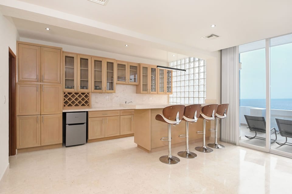 Your modern kitchen opens to a private balcony with stunning sea views. Gather at the sleek breakfast bar or step outside to enjoy the ocean breeze from your terrace.