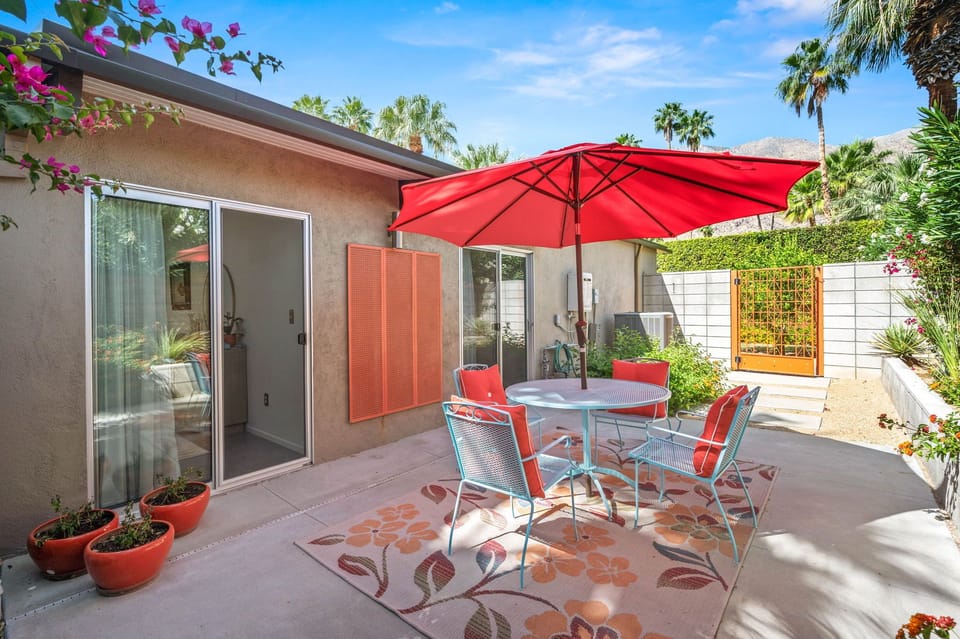 Step onto your private patio where tropical blooms frame your outdoor dining space, complete with vibrant seating and shade for leisurely meals.