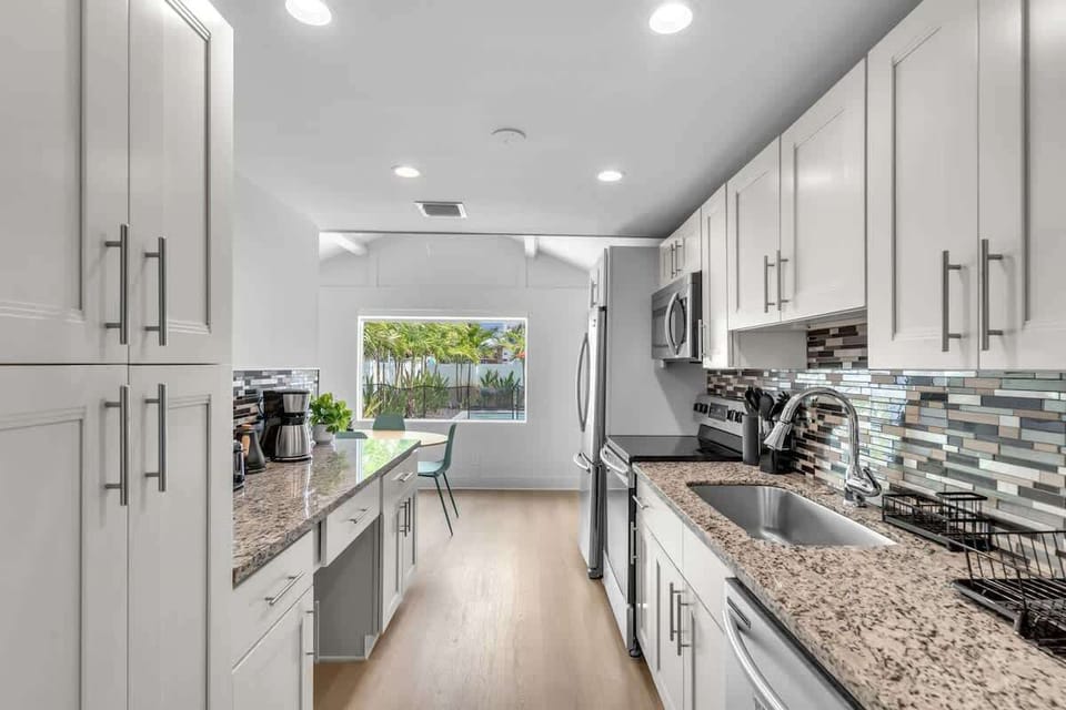 Fully equipped kitchen with granite counters, stainless appliances, and ample cabinetry. A sunny window over the sink and open flow to the dining nook make cooking a pleasure.