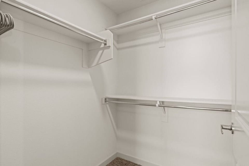 This spacious walk-in closet offers ample storage for clothes, shoes, and more, with multiple shelves and hanging rods to keep everything organized.