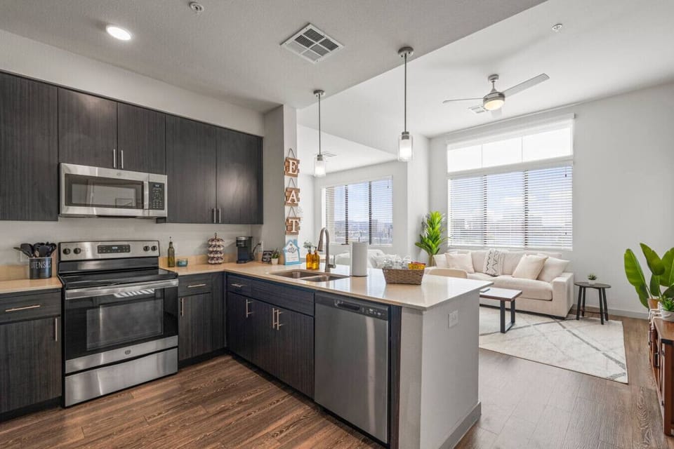 This stylish space features a fully equipped kitchen with stainless steel appliances, a comfortable living area with a large window, and a dining area perfect for meals.