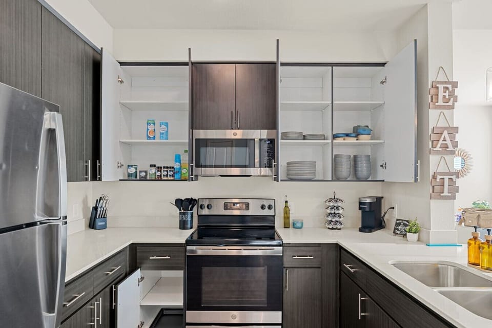 Prepare delicious meals with ease in this fully equipped kitchen, featuring stainless steel appliances, a convenient coffee station, and all the necessary cooking supplies.