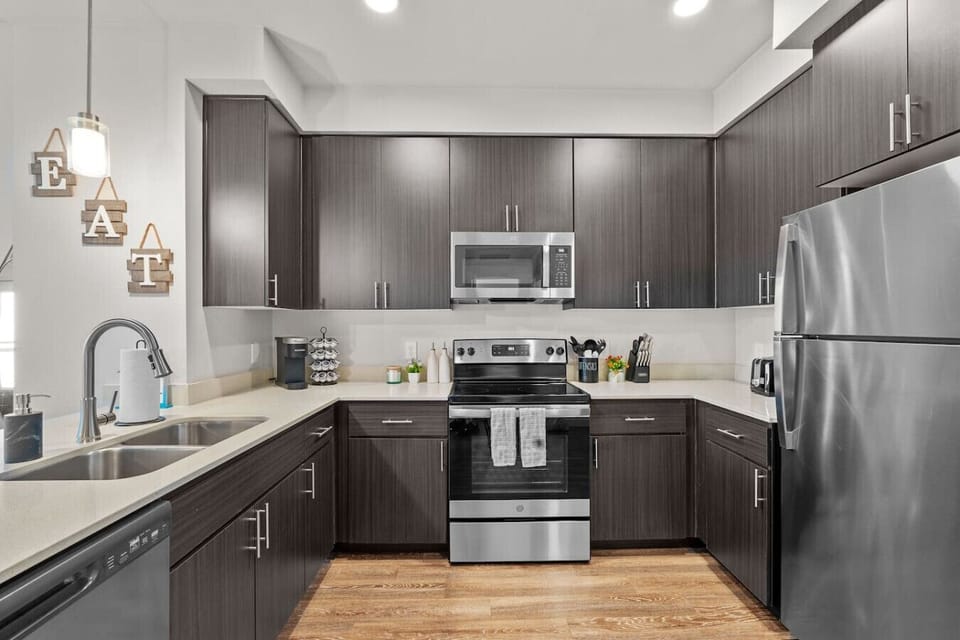 The kitchen features stainless steel appliances, including a refrigerator, stove/oven, and microwave.