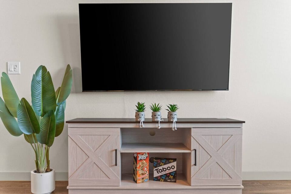 This entertainment area features a mounted flat-screen TV and a console table decorated with charming potted plants.