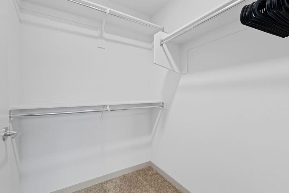 This spacious walk-in closet offers ample storage for clothes, shoes, and more, with multiple shelves and hanging rods to keep everything organized.