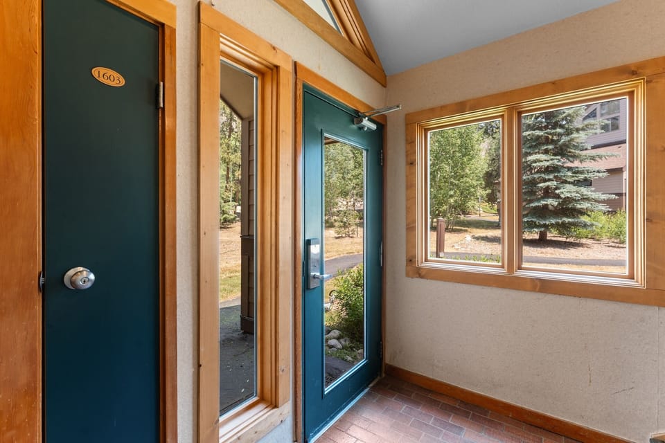 Natural light fills this welcoming entryway with forest views framing your arrival. The warm wood trim and vaulted ceiling create an inviting first impression.