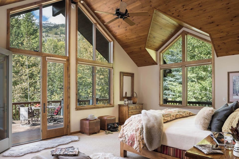 King bed and vaulted ceilings define the primary suite's forest-view bedroom.