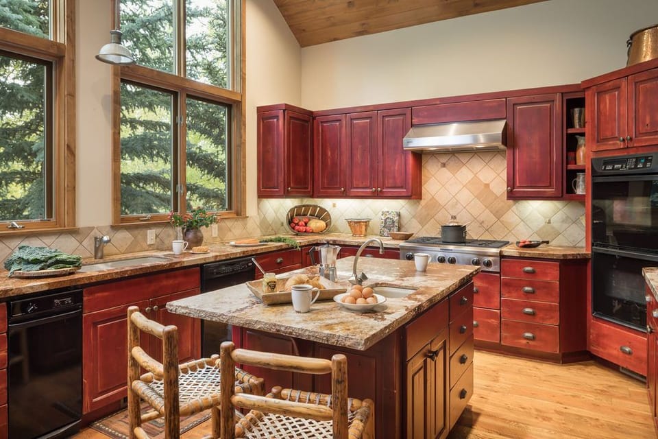 Two barstools sit at the counter, with windows framing the forest beyond as you sip your coffee.