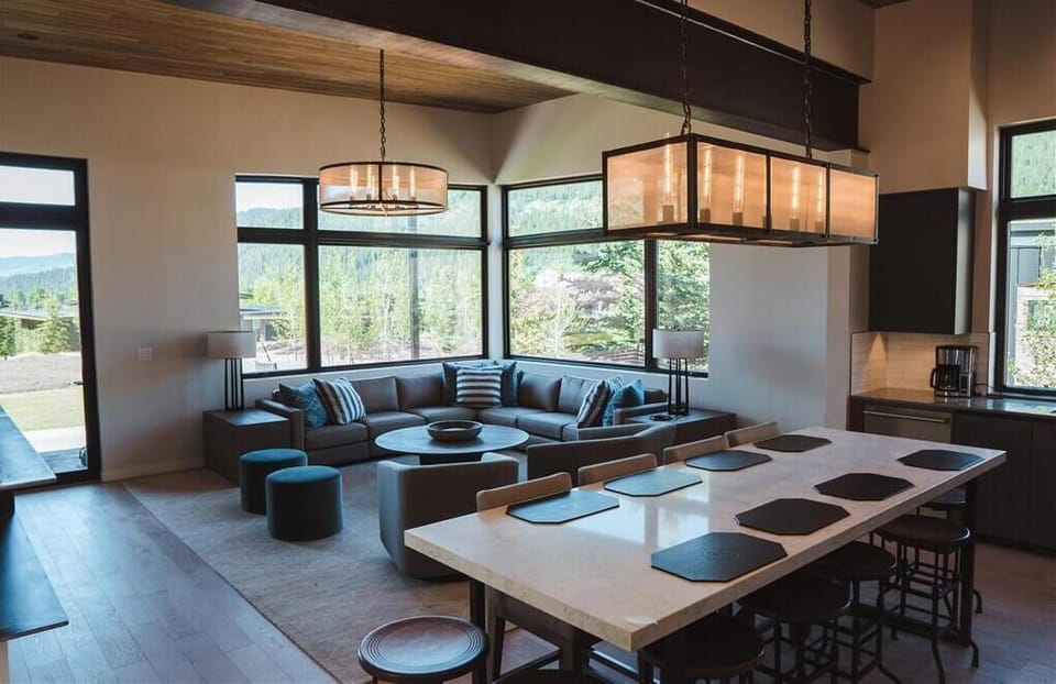 Open living area with a sectional sofa, stone-topped kitchen island, and wood-beam ceiling
