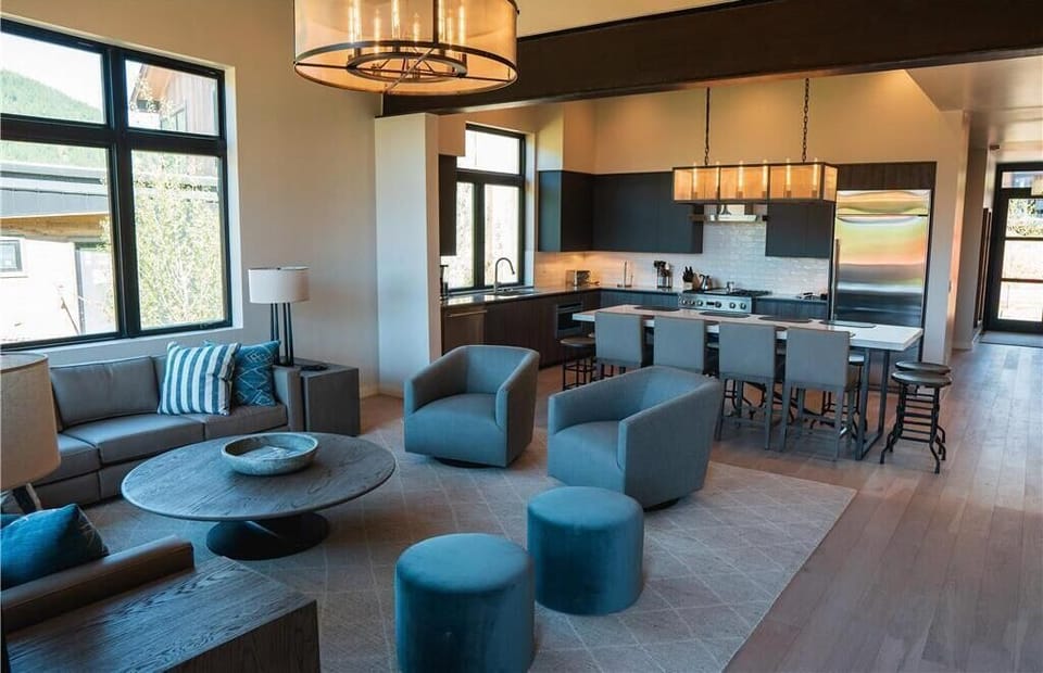 Living area with chairs around a round table, dark cabinetry, and views of greenery through the windows
