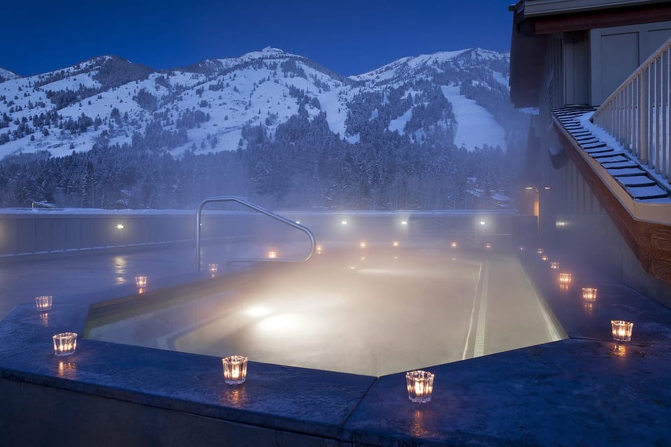 Candles line the rooftop hot tub as dusk settles over the mountains.
