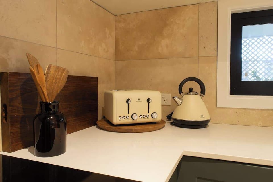 Start your morning right in this cozy kitchen nook, featuring vintage-inspired cream appliances, wooden cooking utensils, and warm tiled backsplashes.