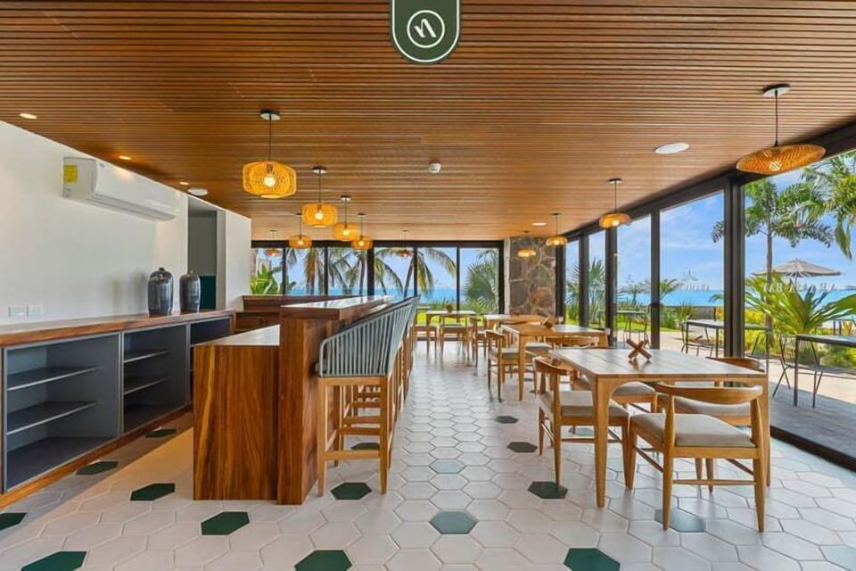 Dine with a view! This beautiful clubhouse space offers a custom wooden bar setup, woven pendant lights, and dining tables.