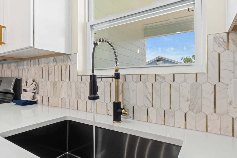 A deep kitchen sink sits just beneath the window, offering plenty of space for cleanup while letting in natural light and views.
