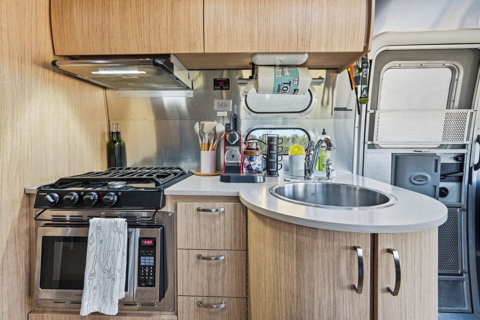 Stylish compact kitchenette with gas stove, coffee maker, and smart storage