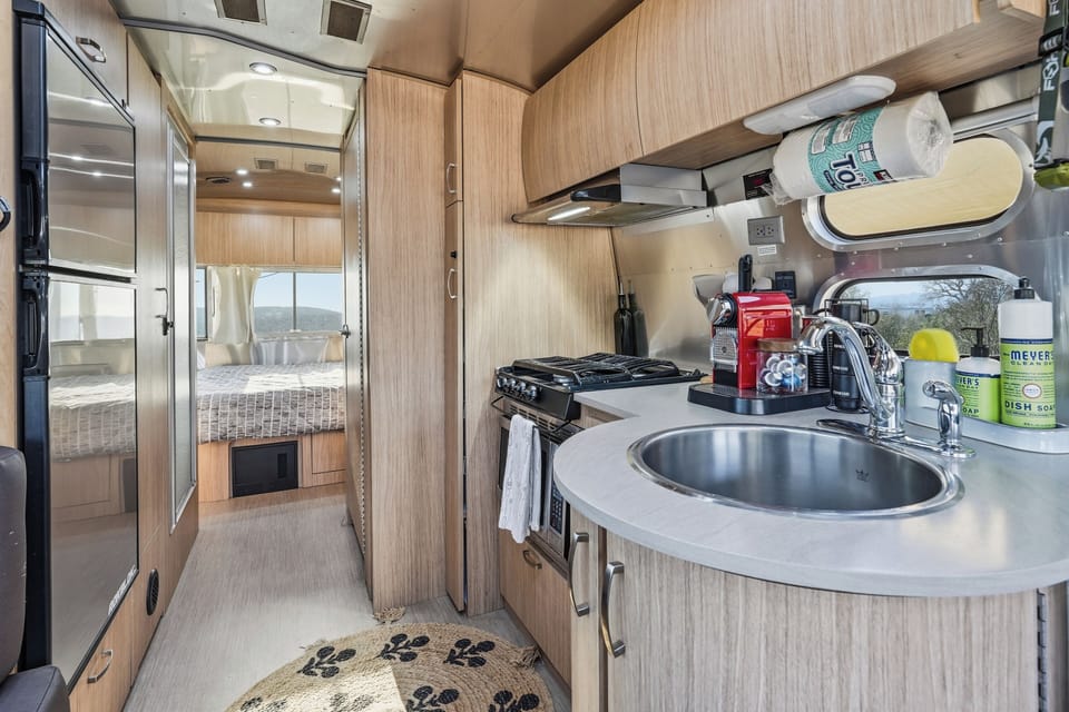 Stylish RV kitchen with coffee station, cooktop, and cozy rear sleeping area