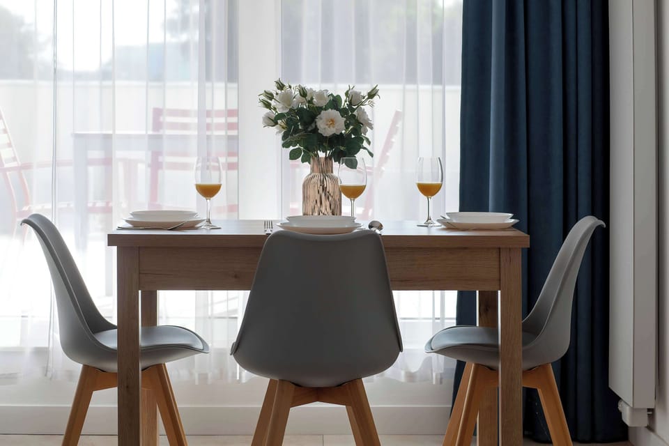 A bright dining area with a table, chairs, and natural light coming through the windows. The simple and elegant setup is perfect for enjoying meals together.