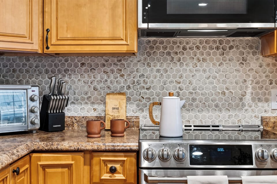 Close-up detail of the kitchen’s chic, textured stone tile backsplash and premium finishes.