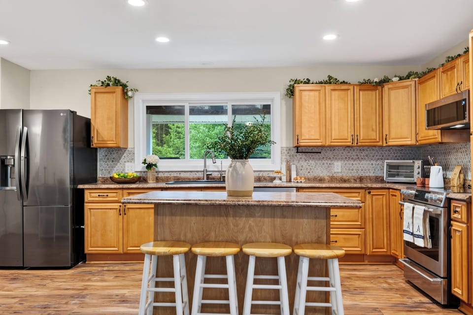 Gourmet kitchen boasting a large center island, warm wood cabinetry, and sleek modern lighting.