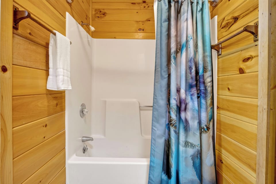 Clean bathroom featuring a full bathtub and shower combination with a decorative shower curtain.