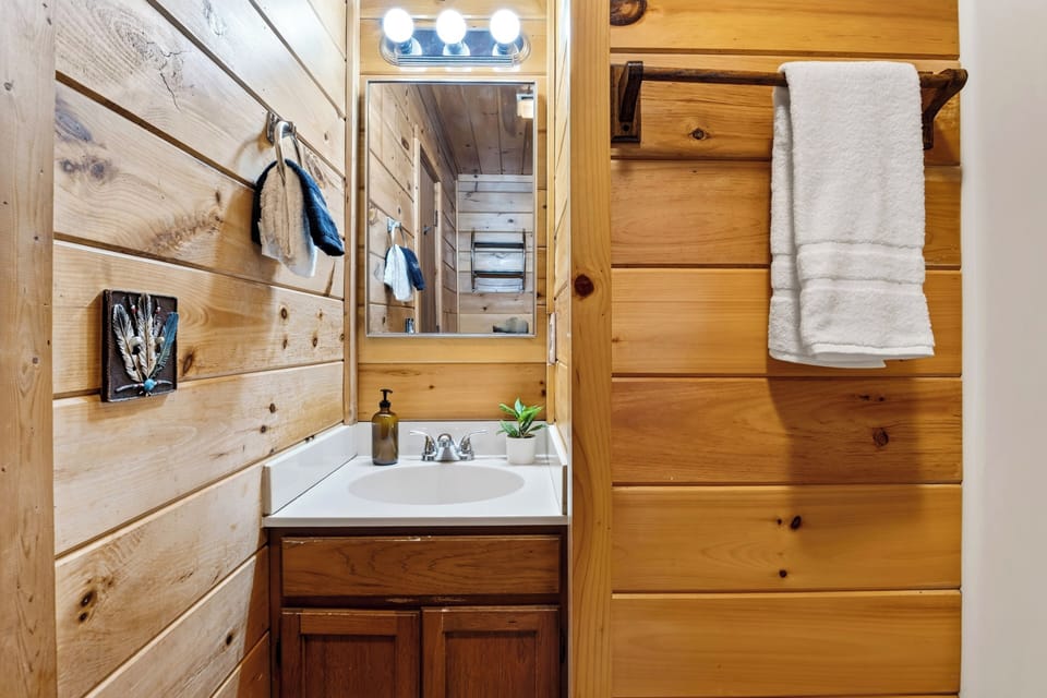 Bathroom vanity with mirror, wall lights, and storage space.