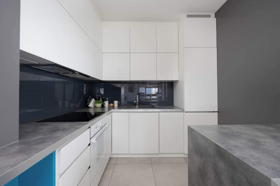 A stylish kitchen with sleek white cabinets and dark countertops. Its minimalist design creates a clean and welcoming atmosphere.