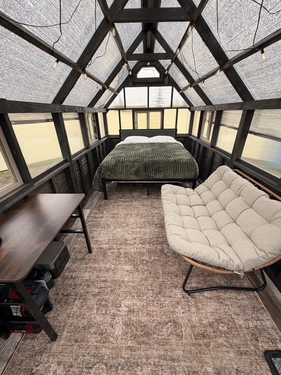 Cozy A-frame glamping retreat with lounge chair, desk, and warm natural light