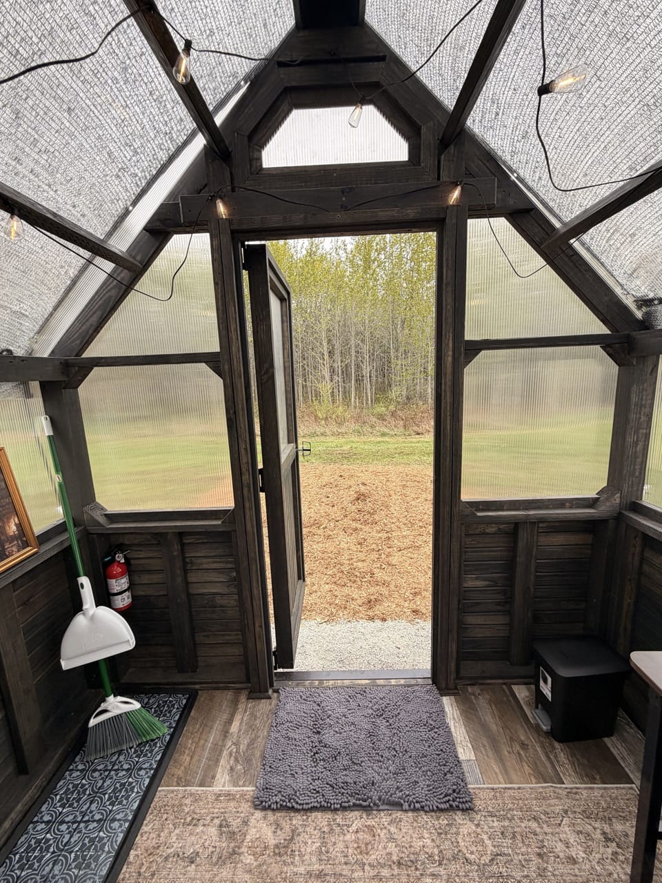 Cozy greenhouse-style retreat with string lights and peaceful forest views