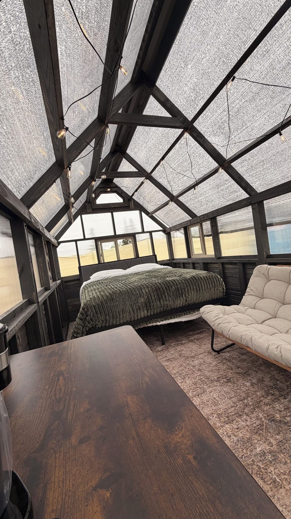 Cozy greenhouse-style retreat with vaulted beams and lounge seating