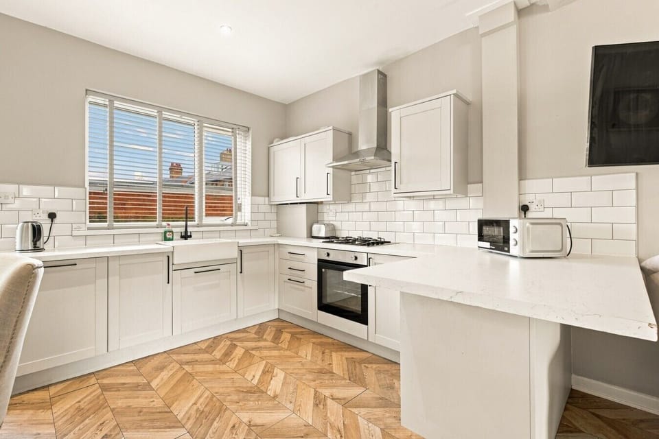 Bright fitted kitchen with breakfast bar and herringbone flooring.