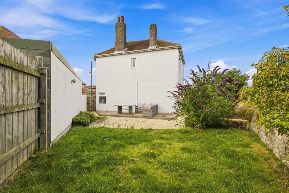 Rear garden with lawn, gravel seating area and enclosed boundaries.