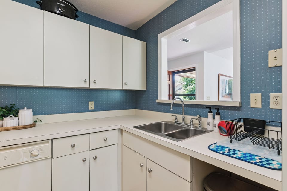 Step into your bright, retro-inspired kitchen with cheerful blue walls and classic white cabinetry. You'll love the double sink and generous counter space, perfect for preparing your favorite meals.