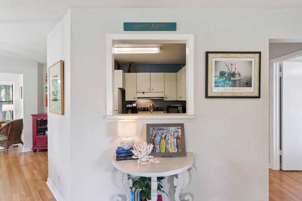 Peek into your coastal kitchen through this charming pass-through window, with nautical touches and beach-inspired decor welcoming you home.