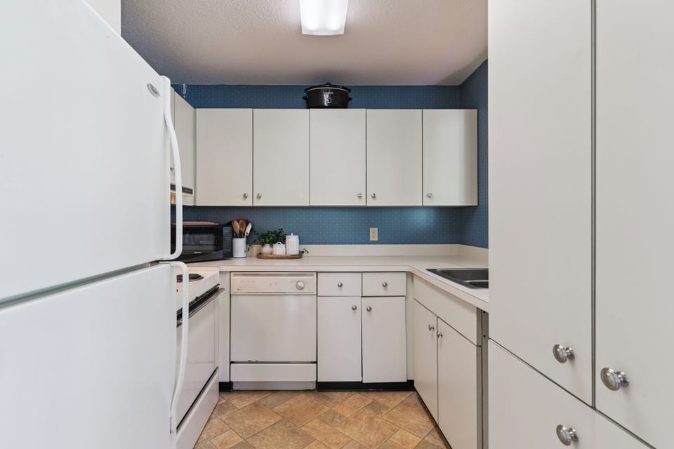 Your fully equipped kitchen features crisp white cabinetry and a charming blue accent wall, with everything you need to prepare meals during your stay.