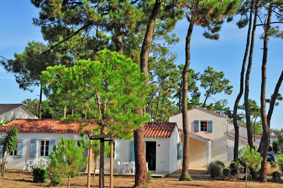 Blue shutters and a red-tiled roof sit tucked among the pines, just a short walk from the pool.