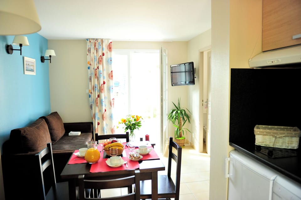 Bright curtains and a glass door open onto the terrace, ready for evenings after the beach.