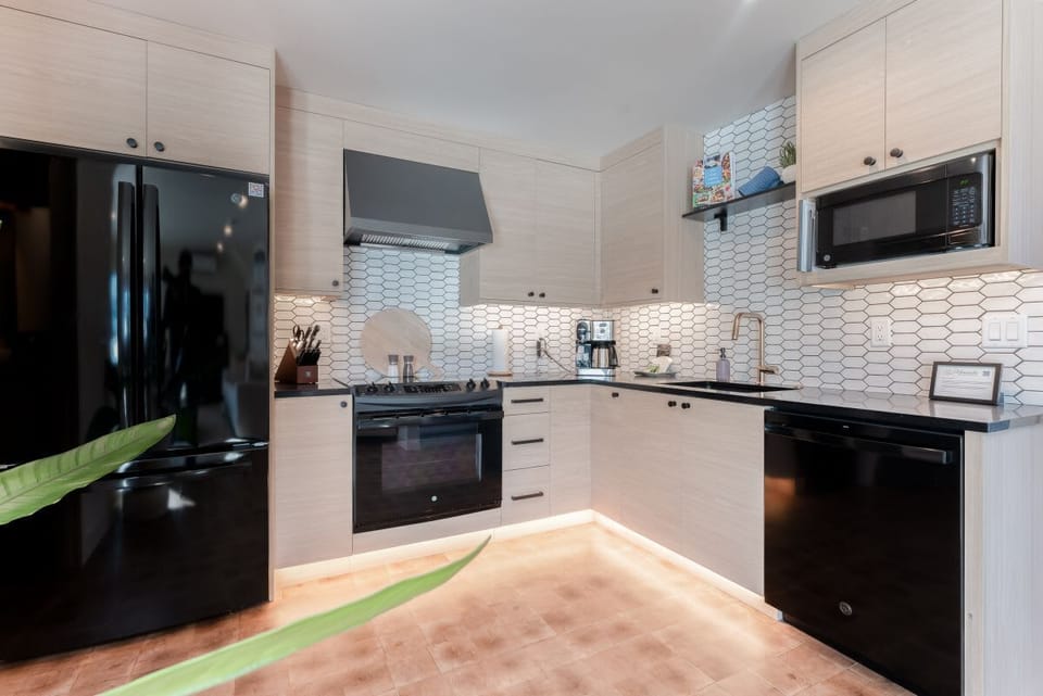 Prepare meals with ease in a modern kitchen outfitted with sleek black appliances, white cabinetry, and stylish tile backsplash.