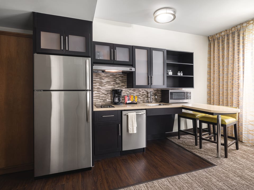 Full kitchen with stainless steel appliances, table, and stools.