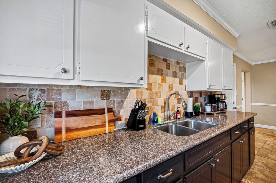 Well-Stocked Kitchen: Feel right at home with a complete suite of cookware essentials, plenty of cabinet storage, sleek black appliances, and clean counter space designed for easy vacation dining.