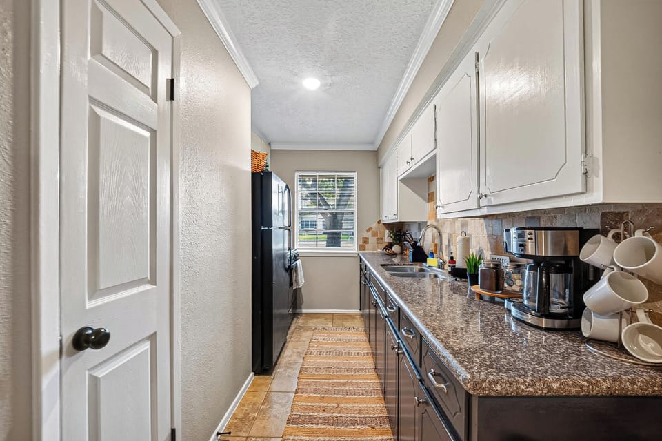 Bright & Functional Kitchen Area: Experience practical functionality with clean lines, neutral tile flooring, bright overhead lighting, and dual-tone cabinetry for all your meal prep needs.