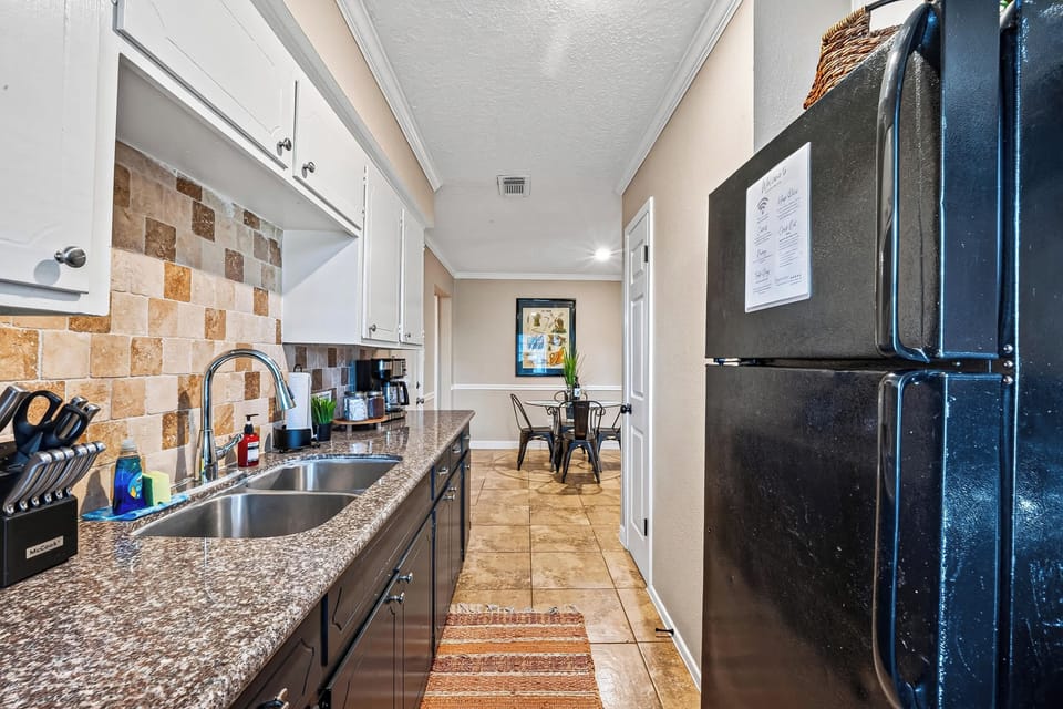 Fully Equipped Kitchen: Prepare home-cooked meals with ease in this galley kitchen, equipped with durable granite-look countertops, clean white upper cabinetry, rich dark lower cabinets, and a double-basin sink.
