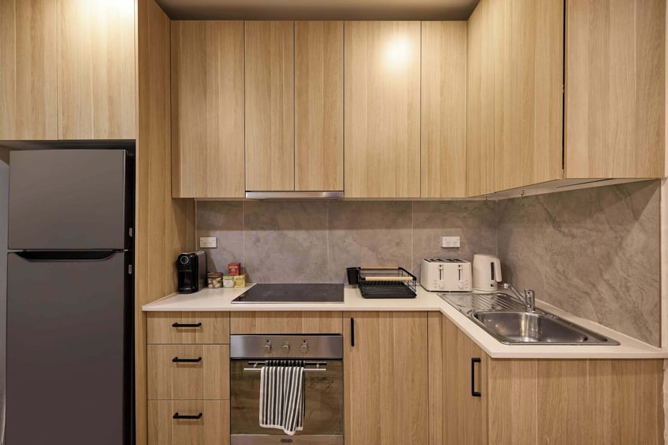 Cook delicious meals with ease in this well-appointed kitchen, featuring custom light wood cabinetry, modern appliances including an integrated oven and cooktop, a refrigerator, and plenty of counter space.