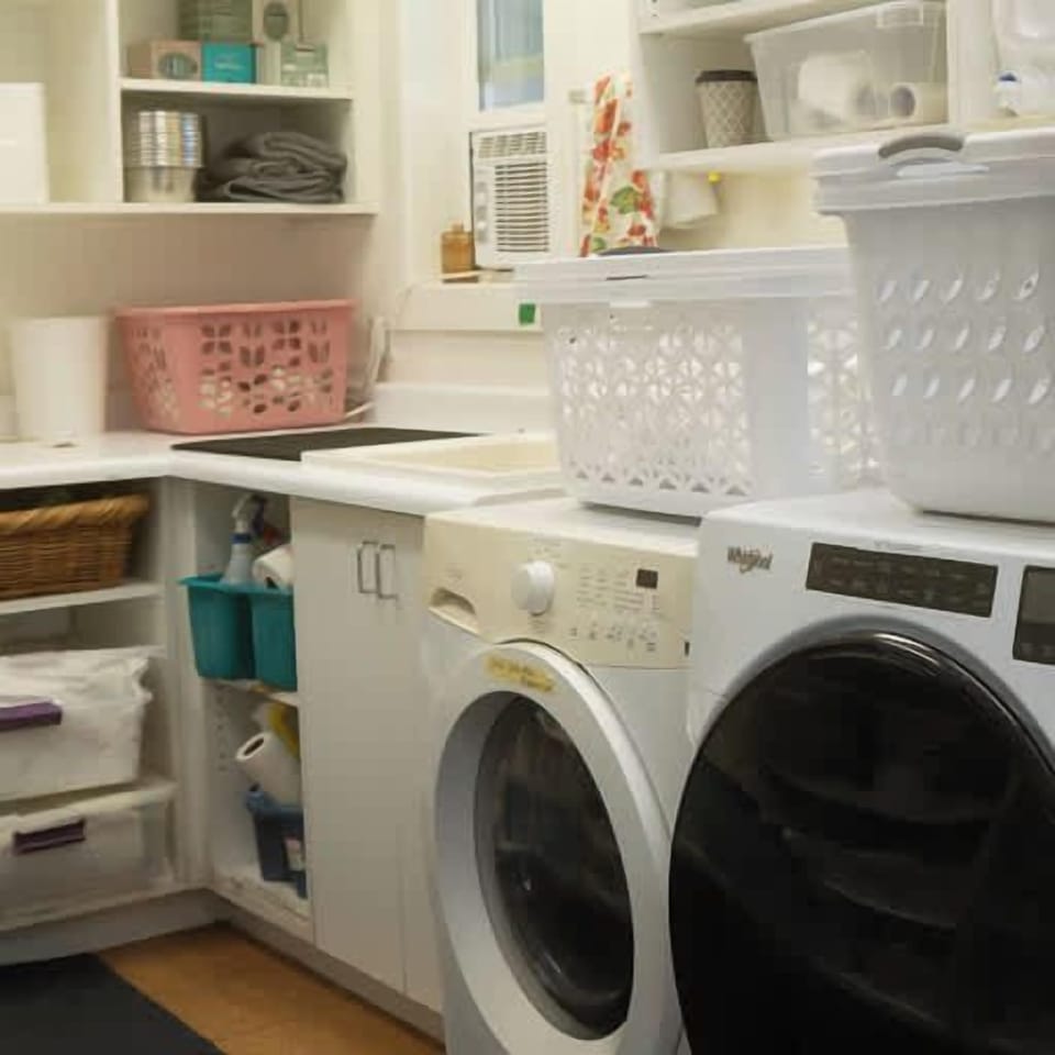 Shared laundry facilities equipped with washing machines, dryer, and storage amenities for guest convenience.