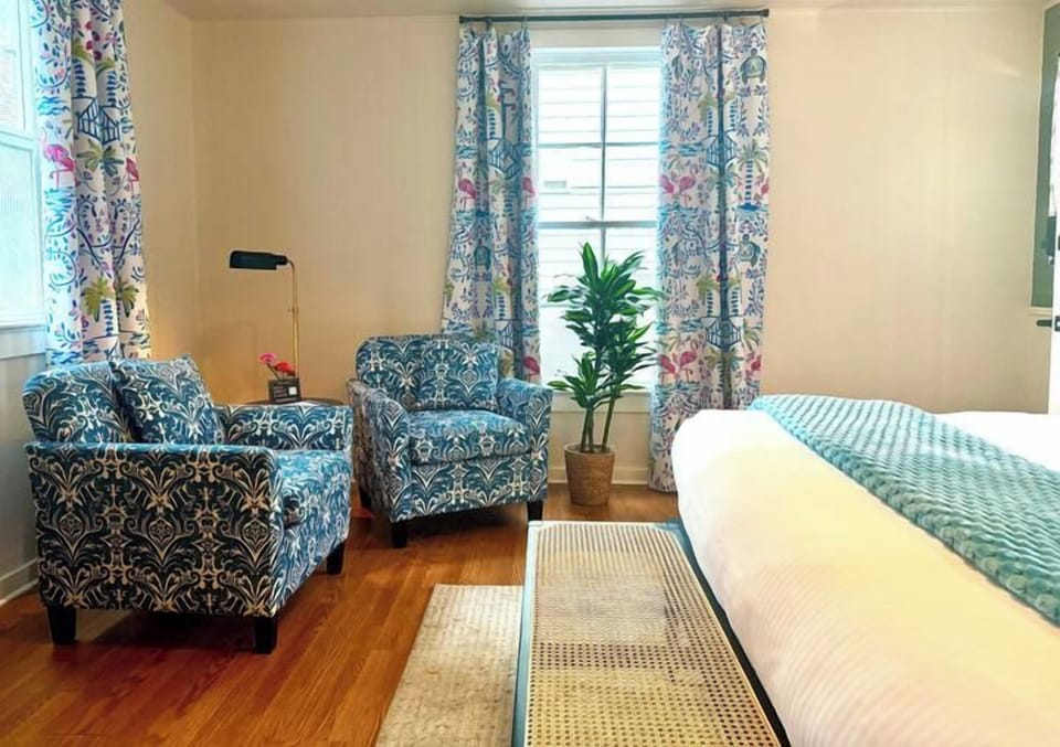Swank 3: Inviting seating area in bedroom featuring two patterned armchairs beside a sunlit window.