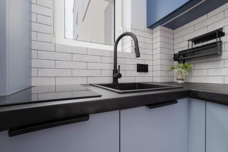 Close-up of the modern kitchen with a black countertop, sink, and subway tile backsplash.