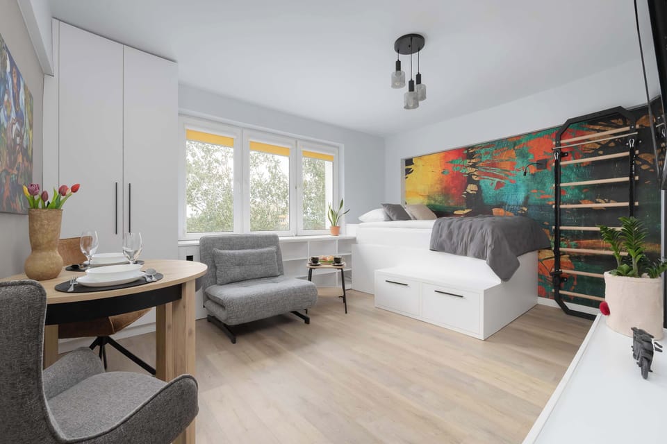 Spacious view of the studio featuring the single bed, single sofa bed, dining area, and large windows.