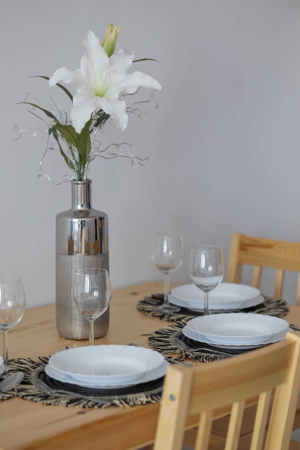 Stylish dining area with wooden table, elegant table setting, and decorative flowers.