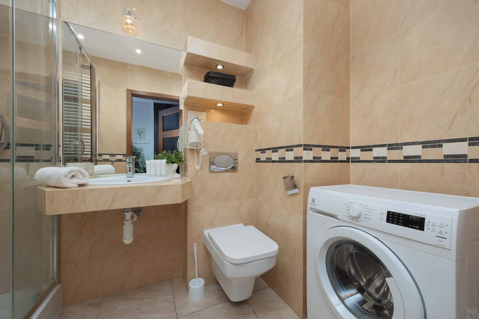 Bathroom with a shower, washing machine and sink.